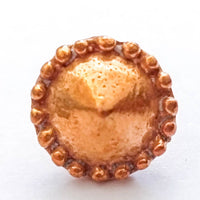 A single round copper-toned button or stud with a textured center and a beaded outer edge, shown on a plain white background.